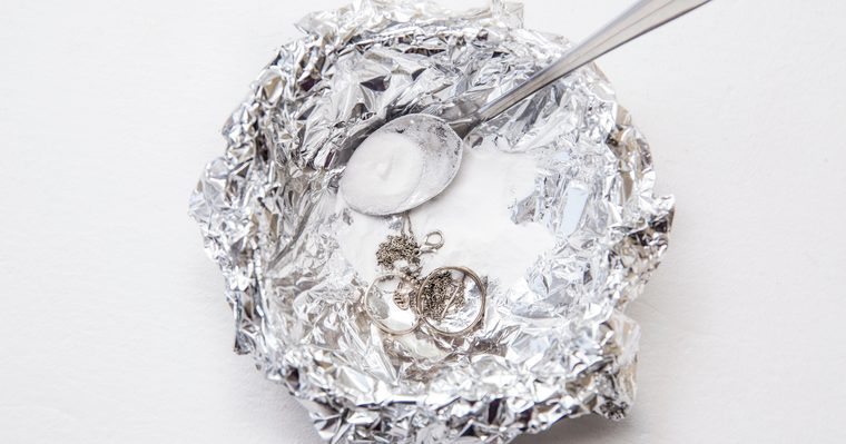 Pieza de plata sobre papel de aluminio en un recipiente con agua