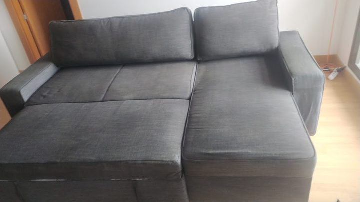 Sofá chaiselongue de tela gris recién limpiado en el salón de un cliente